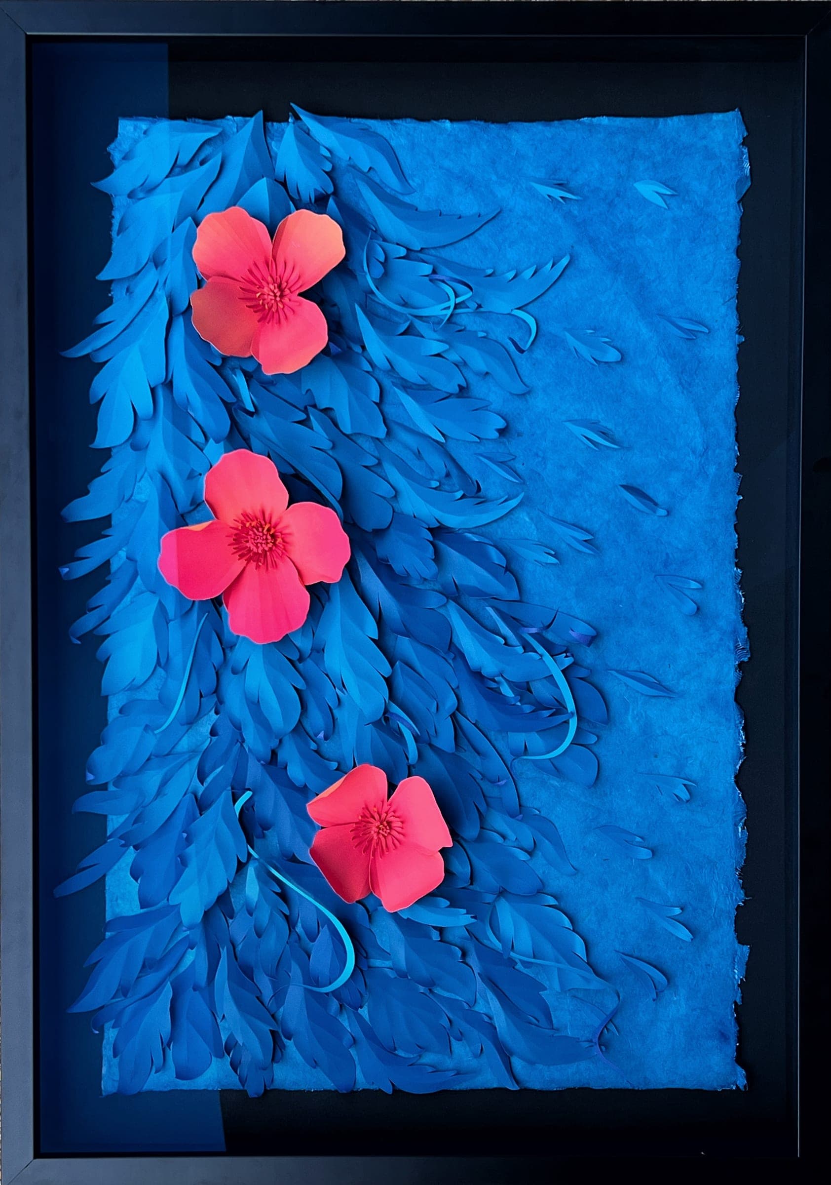 Textured blue relief of layered paper with three pink flowers, in a black frame